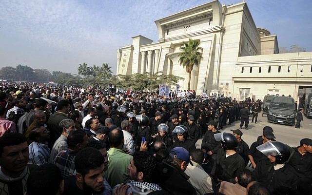 Riot police form a cordon as several thousand supporters of Islamist President Mohammed Morsi surround the Supreme Constitutional Court on Sunday (photo credit: Ahmad Hammad/AP).