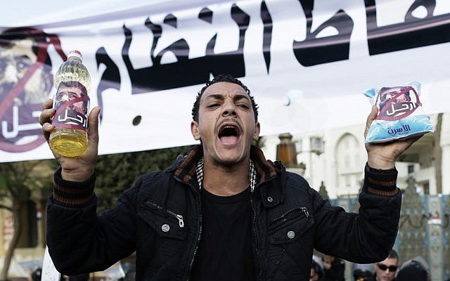An Egyptian protester  chants anti-Muslim Brotherhood and Egyptian President Mohammed Morsi slogans outside the presidential palace under a banner with a defaced picture of president Mohammed Morsi and Arabic that reads 'the people want to bring down the regime,' in Cairo, Egypt, Saturday. (AP Photo/Hassan Ammar)