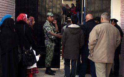 An Egyptian soldier stands guard outside a polling station in Cairo, Egypt, on Saturday as people line up to cast their votes in a referendum on a disputed constitution drafted by Islamist supporters of President Mohammed Morsi (photo credit: AP/Khalil Hamra) An Egyptian soldier stands guard outside a polling station in Cairo, Egypt, on Saturday as people line up to cast their votes in a referendum on a disputed constitution drafted by Islamist supporters of President Mohammed Morsi (photo credit: AP/Khalil Hamra)