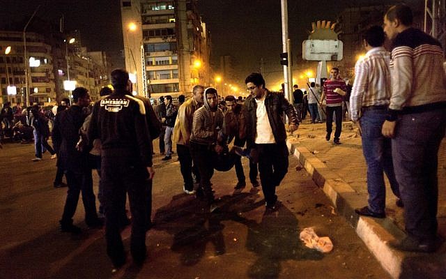 Demonstrators evacuate a wounded protester during anti-Morsi clashes in Cairo Wednesday night. (photo credit:AP/Nasser Nasser)