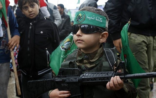 A Palestinian boy wears a green headband with the Arabic slogan "'Ezz Al-Din Al Qassam brigade" and green Islamic flags while holding a toy gun during a rally to commemorate the 25th anniversary of the Hamas militant group, in Gaza City, December 2012. (photo credit: Adel Hana/AP) A Palestinian boy wears a green headband with the Arabic slogan "'Ezz Al-Din Al Qassam brigade" and green Islamic flags while holding a toy gun during a rally to commemorate the 25th anniversary of the Hamas militant group, in Gaza City, December 2012. (photo credit: Adel Hana/AP)
