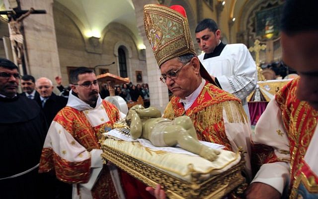 Latin Patriarch of Jerusalem Fouad Twal, center, holds a Baby Jesus statue in Saint Catherine's Church at the end of the Christmas Midnight Mass, and leads the procession to the Grotto, traditionally believed by Christians to be the birthplace of Jesus Christ, at the nearby Church of the Nativity, in Bethlehem on Tuesday, December 25, 2012. (photo credit: AP/Abed Al Hashlamoun, Pool) Latin Patriarch of Jerusalem Fouad Twal, center, holds a Baby Jesus statue in Saint Catherine's Church at the end of the Christmas Midnight Mass, and leads the procession to the Grotto, traditionally believed by Christians to be the birthplace of Jesus Christ, at the nearby Church of the Nativity, in Bethlehem on Tuesday, December 25, 2012. (photo credit: AP/Abed Al Hashlamoun, Pool)