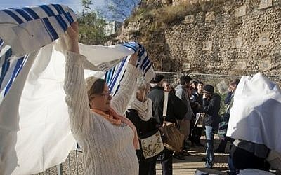 An Israeli member of the Women of the Wall organization dons a prayer shawl just outside the Western Wall in Jerusalem's old city on Friday (photo credit: AP/Dan Balilty)