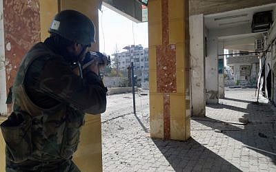 A Syrian soldier aims his rifle at Free Syrian Army fighters during clashes in the Damascus suburb of Daraya on Sunday, Dec. 2, 2012. (photo credit: SANA/AP)
