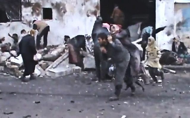 A Syrian man carries an elderly woman after a government airstrike hit the Hama suburb of Halfaya, Syria, on Sunday December 23, 2012. (photo credit: Shaam News Network via AP video) A Syrian man carries an elderly woman after a government airstrike hit the Hama suburb of Halfaya, Syria, on Sunday December 23, 2012. (photo credit: Shaam News Network via AP video)