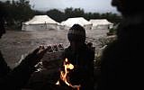 Syrians, who fled their homes with their families, gather around a fire to warm themselves at a makeshift vegetables store in a camp for the displaced in the village of Atmeh, Syria, Tuesday, Dec. 18, 2012. (Photo credit: AP/Muhammed Muheisen)