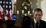 US President Barack Obama greets people as he stands next to a lit menorah during the Hanukkah reception in the Grand Foyer of the White House, Thursday, Dec. 13, 2012, in Washington. (Carolyn Kaster/AP)