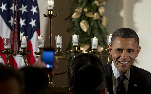US President Barack Obama greets people as he stands next to a lit menorah during the Hanukkah reception in the Grand Foyer of the White House, Thursday, Dec. 13, 2012, in Washington. (Carolyn Kaster/AP)