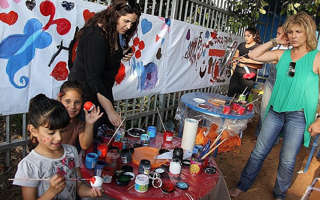 Children in Ramat Hasharon paint with volunteers from Takdim, an Israeli charity modeled on the Jewish federation system in the US. (Courtesy of Takdim via jTA)