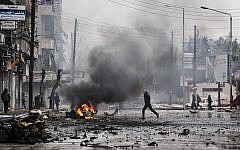 A man runs through the debris after a mortar shell hit a street, killing several people, in the Bustan Al-Qasr district of Aleppo, Syria, December 2012 (photo credit: AP/Narciso Contreras)