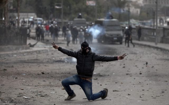 A masked Egyptian protester part of the Black Bloc, flashes the victory sign during clashes with riot police, background, near Tahrir Square, Cairo, Egypt, Monday, Jan. 28, 2013 (photo credit: AP/Khalil Hamra) A masked Egyptian protester part of the Black Bloc, flashes the victory sign during clashes with riot police, background, near Tahrir Square, Cairo, Egypt, Monday, Jan. 28, 2013 (photo credit: AP/Khalil Hamra)