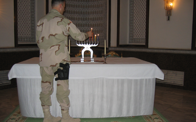Maj. Elan Carr lights Hanukkah candles in late 2003 in a Baghdad palace formerly inhabited by Saddam Hussein. (Courtesy of Elan Carr)