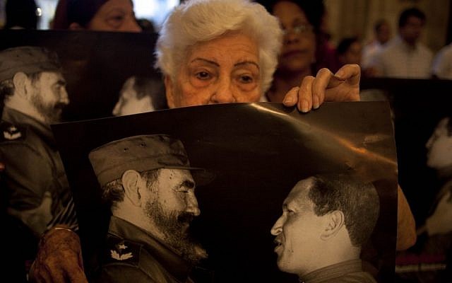 Parishioners hold posters that show Cuba's Fidel Castro, left, and Venezuela's President Hugo Chavez, during a mass to pray for the recovery of Chavez at the Cathedral, in Havana, Cuba, in January 2013 (photo credit: AP/Ramon Espinosa) Parishioners hold posters that show Cuba's Fidel Castro, left, and Venezuela's President Hugo Chavez, during a mass to pray for the recovery of Chavez at the Cathedral, in Havana, Cuba, in January 2013 (photo credit: AP/Ramon Espinosa)