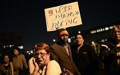 Illustrative photo of protesters holding up a sign that reads 'Help! The neighborhoods are sinking,' at an anti-migrant demonstration in Tel Aviv (photo credit: Tomer Neuberg/Flash90)