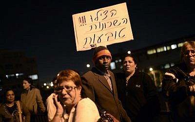 Illustrative photo of protesters holding up a sign that reads 'Help! The neighborhoods are sinking,' at an anti-migrant demonstration in Tel Aviv (photo credit: Tomer Neuberg/Flash90)