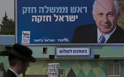 An ultra-Orthodox Jew walks in front of a campaign posters for the Likud-Yisrael Beitenu party in Jerusalem on Friday. (photo credit:Yonatan Sindel/Flash90)