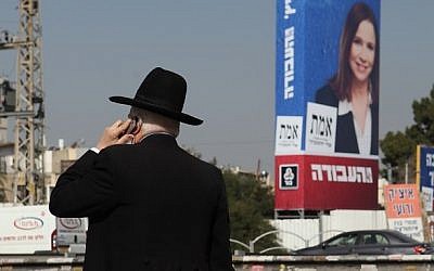 An ultra-Orthodox Jewish man seen next to a large election campaign poster showing the leader of the Labor party, Shelly Yachimovich, in the Orthodox neighborhood of Bnei Brak, Thursday. (photo credit: Yaakov Naumi/Flash90)