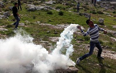 Palestinians hurl rocks at Israeli soldiers during a demonstration in the village of Budrus, west of Ramallah, Friday. (photo credit: Issam Rimawi/Flash90)