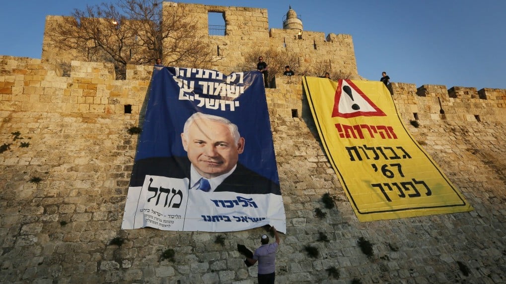 Supporters of Prime Minister Benjamin Netanyahu and his Likud party unfold large posters depicting Netanyahu reading "Only Netanyahu will protect Jerusalem" and "The borders of '67 in front of you," at the Old City walls, January 20, 2013. (Photo credit: Miriam Alster/FLASH90)