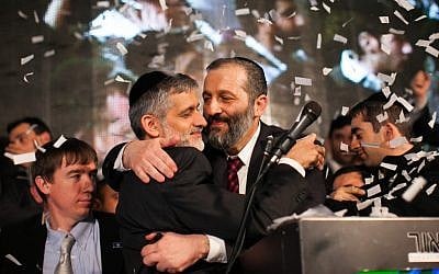 Shas chairman Eli Yishai and the party's #2, Aryeh Deri, hug at the Shas headquarters in Jerusalem as the results of the exit polls in the general elections for Israel's 19th Knesset are announced, Tuesday. (photo credit: Yonatan Sindel/Flash90)