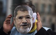 A man covers his face with a mask of Egypt President Mohammed Morsi during a protest in front of the chancellery in Berlin, Germany, Wednesday, Jan. 30, 2013. (photo credit: AP/Markus Schreiber)