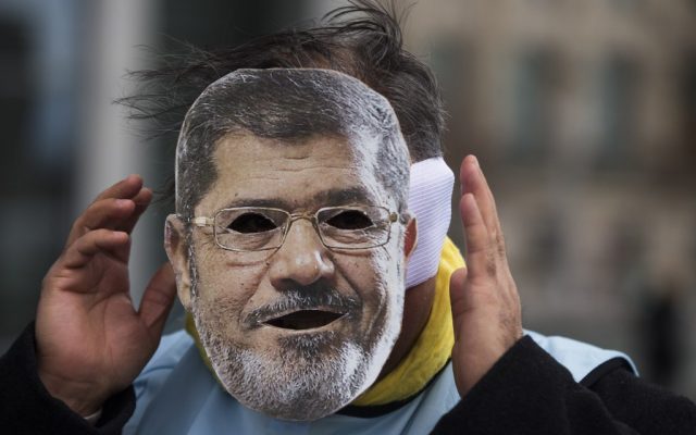 A man covers his face with a mask of Egypt President Mohammed Morsi during a protest in front of the chancellery in Berlin, Germany, Wednesday, Jan. 30, 2013. (photo credit: AP/Markus Schreiber) A man covers his face with a mask of Egypt President Mohammed Morsi during a protest in front of the chancellery in Berlin, Germany, Wednesday, Jan. 30, 2013. (photo credit: AP/Markus Schreiber)