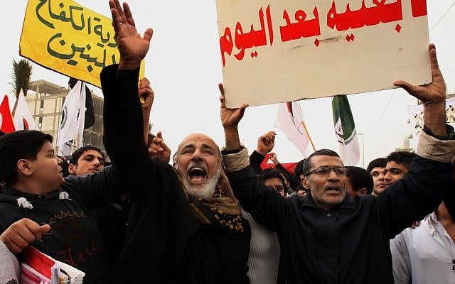 Protesters chant pro-Iraqi Prime Minister Nouri al-Maliki slogans during a demonstration in Basra, Iraq, on Tuesday, January 8, 2013. The poster on the right reads, 'No Baathists after today.' (photo credit: AP/Nabil al-Jurani)
