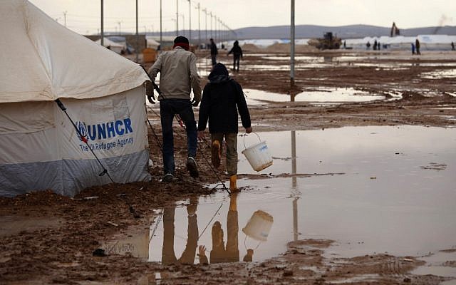 Syrian refugees walk through water and mud in the Zaatari Syrian refugee camp, near the Syrian border in Mafraq, Jordan, Tuesday, Jan. 8, 2013. (photo credit:AP /Mohammad Hannon)