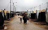 Syrian refugees carry their belongings through the Zaatari camp, located near the Syrian border in Mafraq, Jordan, last winter (photo credit: AP/Mohammad Hannon/File)