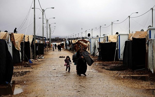 Syrian refugees carry their belongings through the Zaatari camp, located near the Syrian border in Mafraq, Jordan, last winter (photo credit: AP/Mohammad Hannon/File) Syrian refugees carry their belongings through the Zaatari camp, located near the Syrian border in Mafraq, Jordan, last winter (photo credit: AP/Mohammad Hannon/File)
