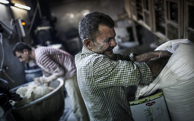 Men make bread at a bakery in the old city of Aleppo (photo credit: Andoni Lubaki/AP)