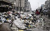 A family crosses a street piled with rubbish in Aleppo, Syria, Saturday, Jan. 5, 2013 (photo credit: AP/Andony Lubaki)