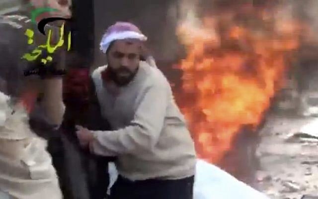 This image shows a wounded man being pulled from the site of a Syrian government airstrike on a gas station in the eastern Damascus suburb of Mleiha, Syria, on Wednesday, January 2, 2013. (photo credit: AP Photo/Shaam News Network via AP video)