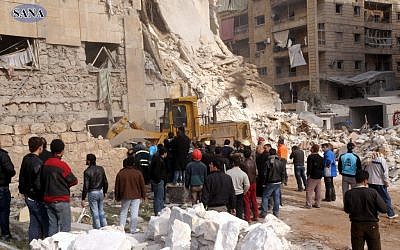 This photo released by the Syrian official news agency, SANA, shows rescue workers and bystanders at a building damaged by a rocket attack that killed at least 12 people in Aleppo, Syria, Friday. (AP Photo/SANA) This photo released by the Syrian official news agency, SANA, shows rescue workers and bystanders at a building damaged by a rocket attack that killed at least 12 people in Aleppo, Syria, Friday. (AP Photo/SANA)