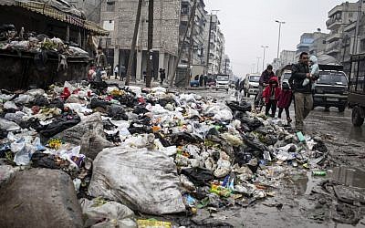 A family crosses a street piled with rubbish in Aleppo, Syria, Saturday, Jan. 5, 2013 (photo credit: AP/Andony Lubaki)