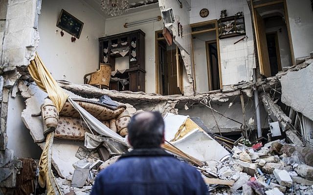 A civilian looks at a building that was destroyed by a Syrian Air Force attack in Aleppo, Syria, on Thursday (photo credit: AP/Andoni Lubaki)