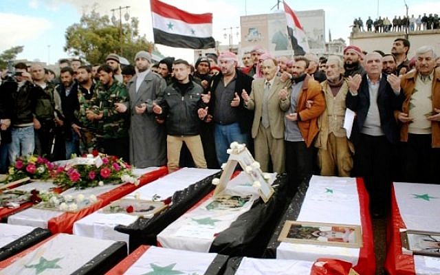 Syrians take part in a funeral procession for those killed in a car bomb explosion at the headquarters of a pro-government militia in Hama province, Syria, on Wednesday (photo credit: AP/SANA)