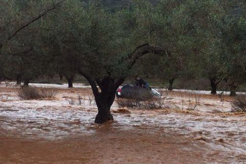 Driver whose car was swept away by the Hilazon stream sits on the top of the vehicle while waiting for rescue workers to arrive (photo credit: Israel Police via Facebook)