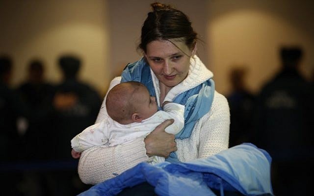 A Russian woman holds her baby while leaving passport control zone just after their arrival from Beirut in Moscow Domodedovo airport, Russia, Wednesday, Jan. 23, 2013 (photo credit: AP/Alexander Zemlianichenko)