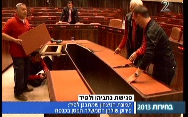 Workers disassemble the cabinet table in the Knesset's plenum (image capture: Channel 2)