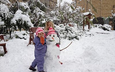 A girl hugging a snowman (photo credit: Mitch Ginsburg/Times of Israel staff)