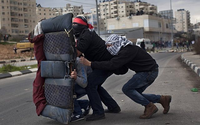 Masked Palestinians use a car seat as a shield during a protest to support Palestinian prisoners, outside the Ofer Prison near the West Bank city of Ramallah, Tuesday, Feb. 19 (photo credit: AP/Bernat Armangue) Masked Palestinians use a car seat as a shield during a protest to support Palestinian prisoners, outside the Ofer Prison near the West Bank city of Ramallah, Tuesday, Feb. 19 (photo credit: AP/Bernat Armangue)