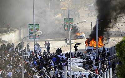 Cars burn next to the cemetery where thousands of Tunisians are gathered at el Jallez cemetery to attend the funerals of slain opposition leader Chokri Belaid, near Tunis, Friday Feb. 8 (photo credit: AP/Hassene Dridi)