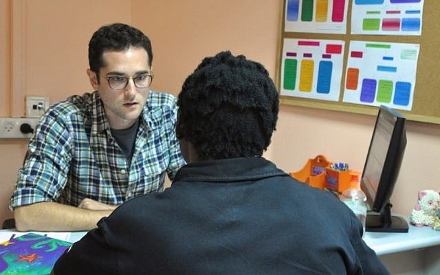 Jonah Mink, the founder of the MigrantHealth:IL public health pilot program, speaks to a patient from Eritrea at the Tel Aviv Refugee Clinic (photo credit: Michal Shmulovich/Times of Israel)
