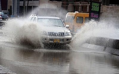 Illustrative photo of a car driving on a flooded street (photo credit: Issam Rimawi/Flash90)