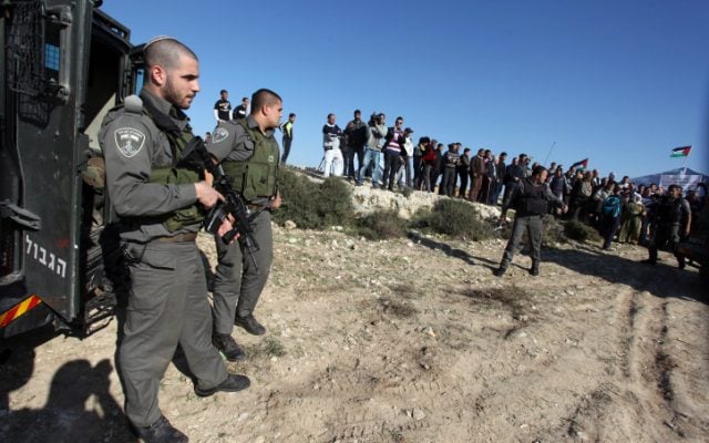 An Israeli border policeman stands in front of Palestinian activists in preparation to removing an outpost, January 19, 2013. (photo credit: Issam Rimawi/Flash90) An Israeli border policeman stands in front of Palestinian activists in preparation to removing an outpost, January 19, 2013. (photo credit: Issam Rimawi/Flash90)