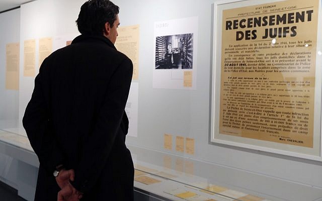 A man looks at a poster reading "Census of Jews" displayed in an exhibition at the Shoah Memorial in Paris, Tuesday, Feb. 12, 2013. The French state prepares to give back seven stolen Nazi-era paintings - 4 of which are in the Louvre - to two Jewish families, after a decade-long tug of war. (photo credit: AP/Jacques Brinon) A man looks at a poster reading "Census of Jews" displayed in an exhibition at the Shoah Memorial in Paris, Tuesday, Feb. 12, 2013. The French state prepares to give back seven stolen Nazi-era paintings - 4 of which are in the Louvre - to two Jewish families, after a decade-long tug of war. (photo credit: AP/Jacques Brinon)