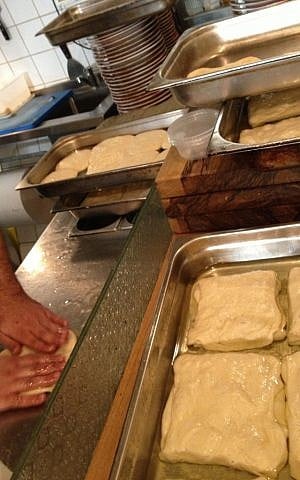 Rolling and folding squares of mufleta (photo credit: Jessica Steinberg/Times of Israel)