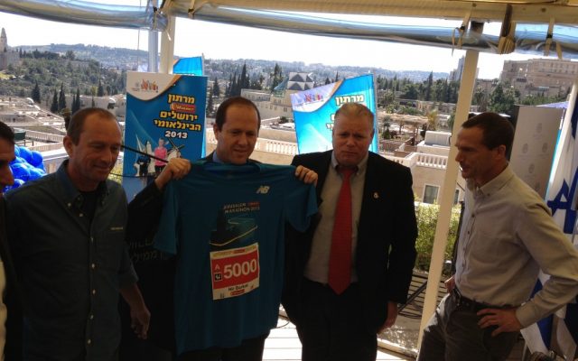 Mayor Nir Barkat holding up his New Balance Jerusalem Marathon 2013 running shirt (photo credit: Jessica Steinberg/Times of Israel) Mayor Nir Barkat holding up his New Balance Jerusalem Marathon 2013 running shirt (photo credit: Jessica Steinberg/Times of Israel)