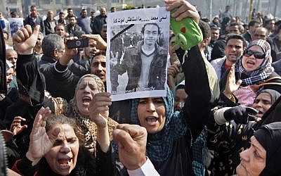 Egyptian relatives of Mohammed el-Gindy, a 28-year-old activist, who died of wounds sustained during clashes near the presidential palace, display his picture as they shout anti-president Morsi slogans during his funeral procession in Tahrir Square, Cairo, on February 4. (photo credit: Amr Nabil/AP)